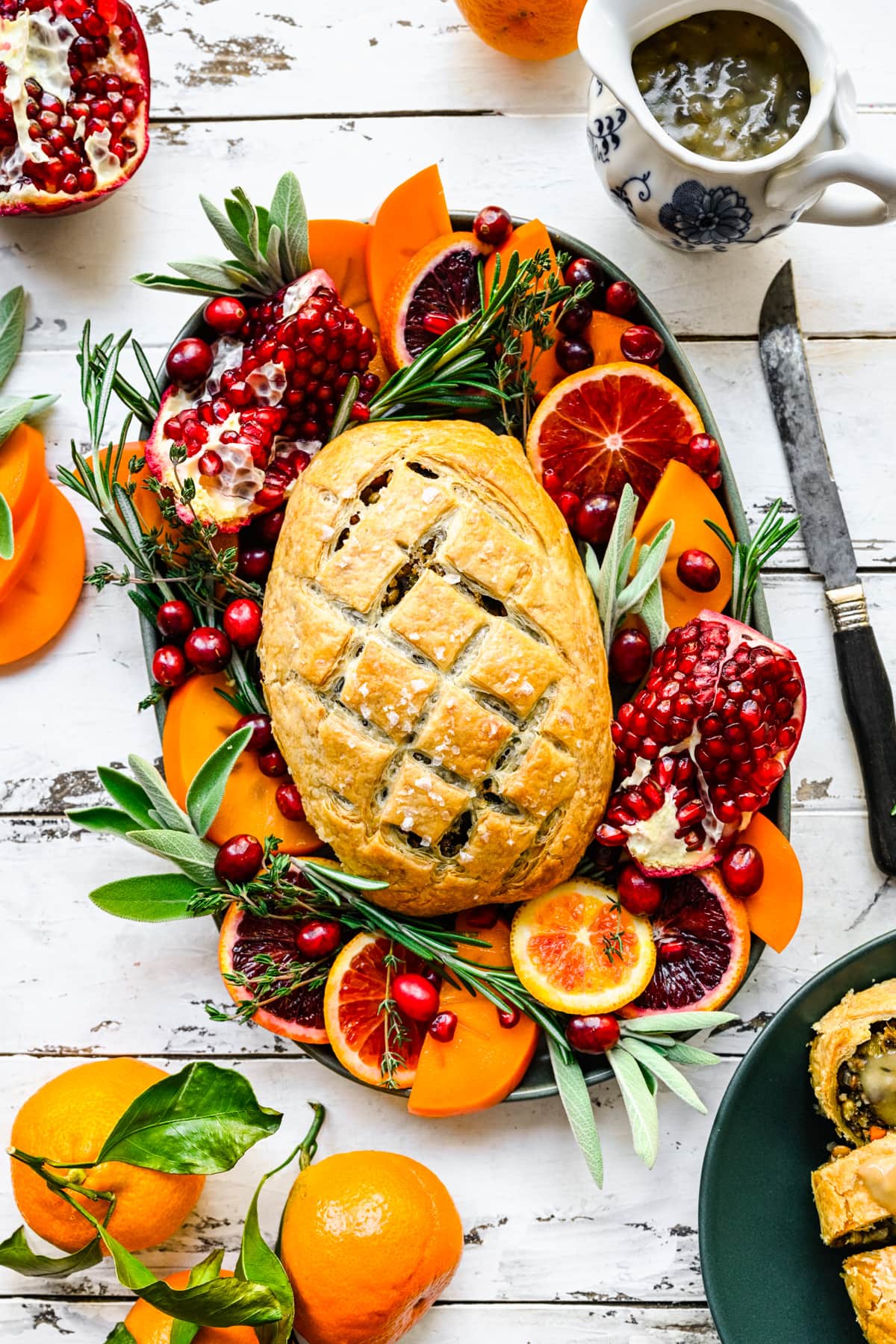 Overhead view of vegan wellington on platter with fruits and herbs.