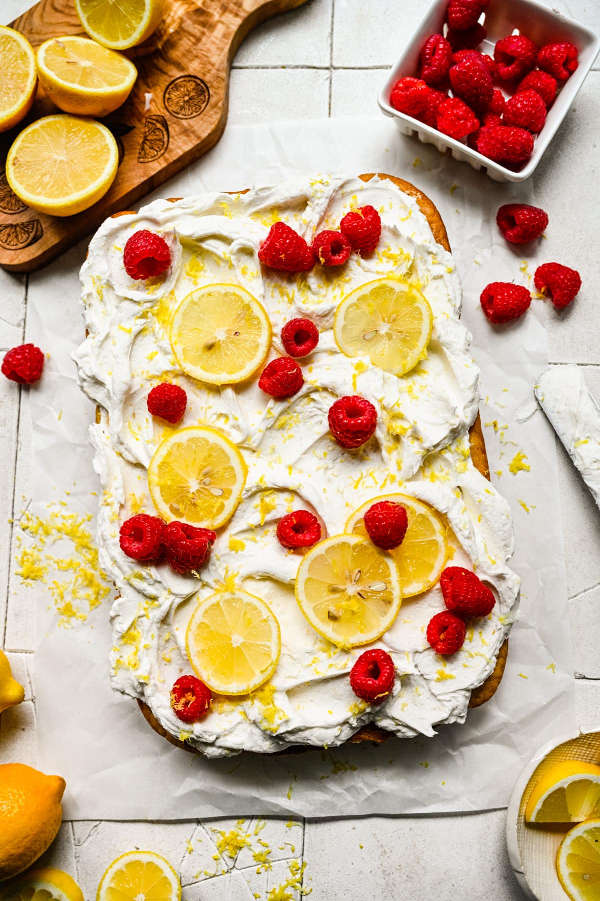 Finished vegan lemon cake topped with lemon slices and raspberries.