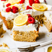 Finished slice of lemon cake with raspberries and lemon slice on top.