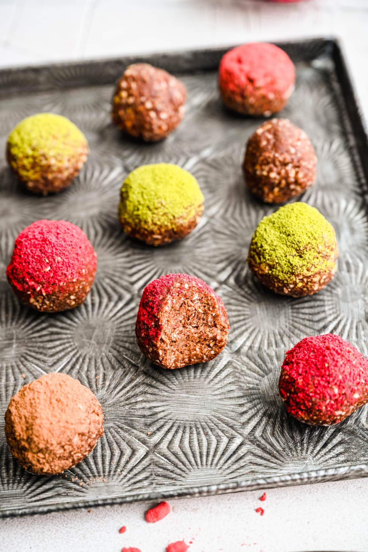 Finished chocolate bliss balls on a silver tray, showing the interior texture of one of them.