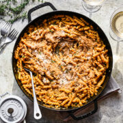 Overhead view of french onion pasta in large skillet with serving spoon.
