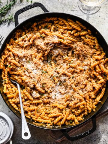 Overhead view of french onion pasta in large skillet with serving spoon.