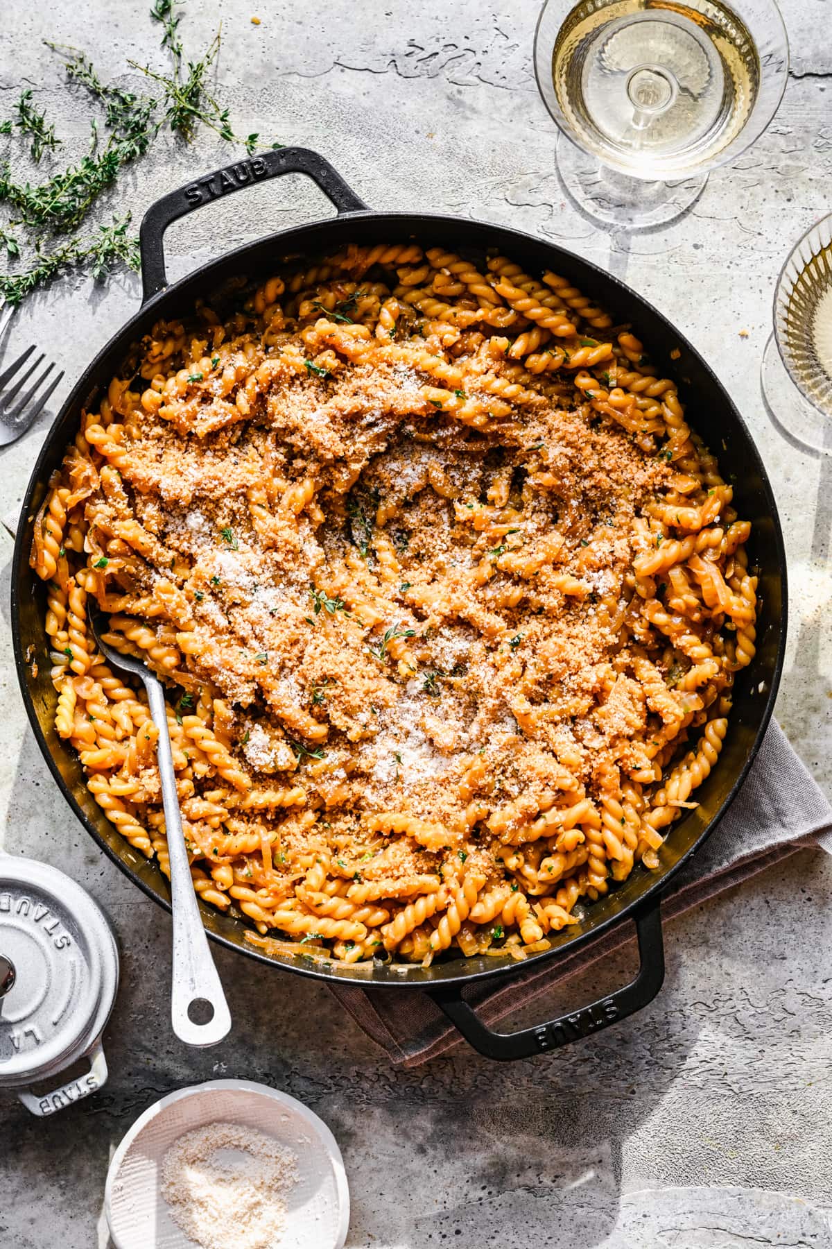 Overhead view of french onion pasta in large skillet with serving spoon. 