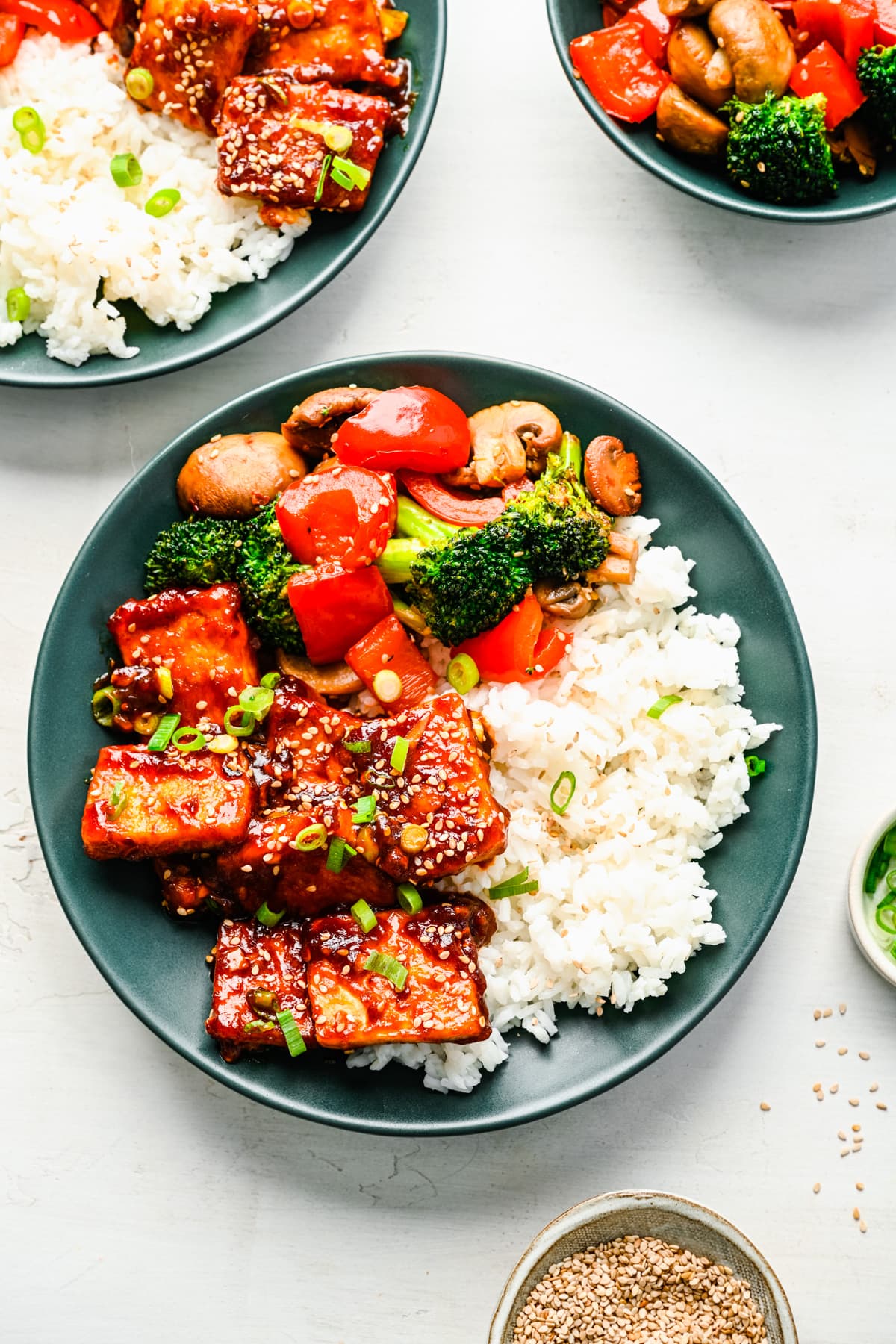 overhead view of sticky tofu on plate with stir fried vegetables and white rice. 