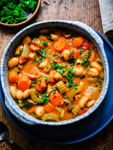 Overhead of the finished butter bean stew in a blue bowl.