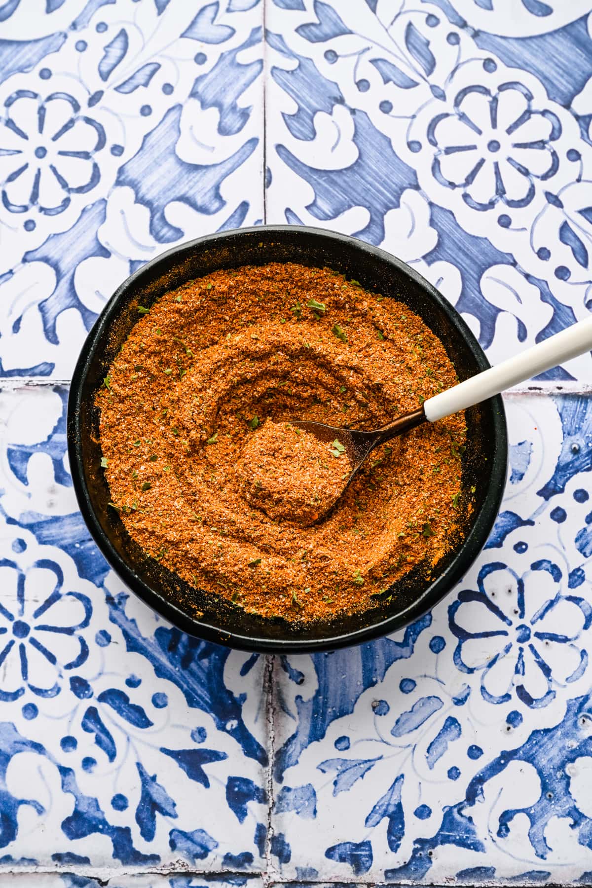 Finished spice blend in a bowl on a patterned background.