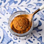 A spoon scooping some of the spice blend out of a jar.