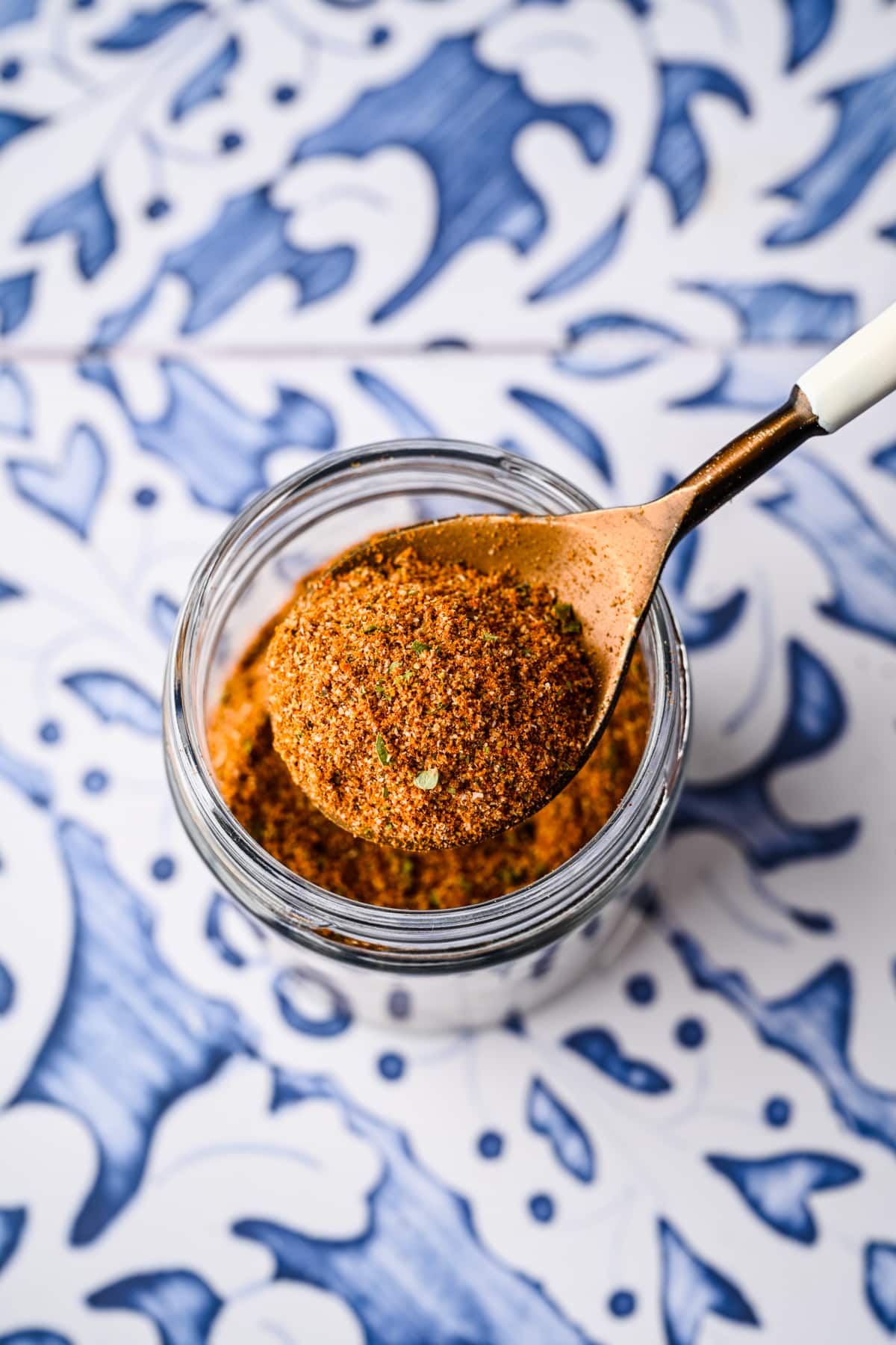 A spoon scooping some of the spice blend out of a jar.