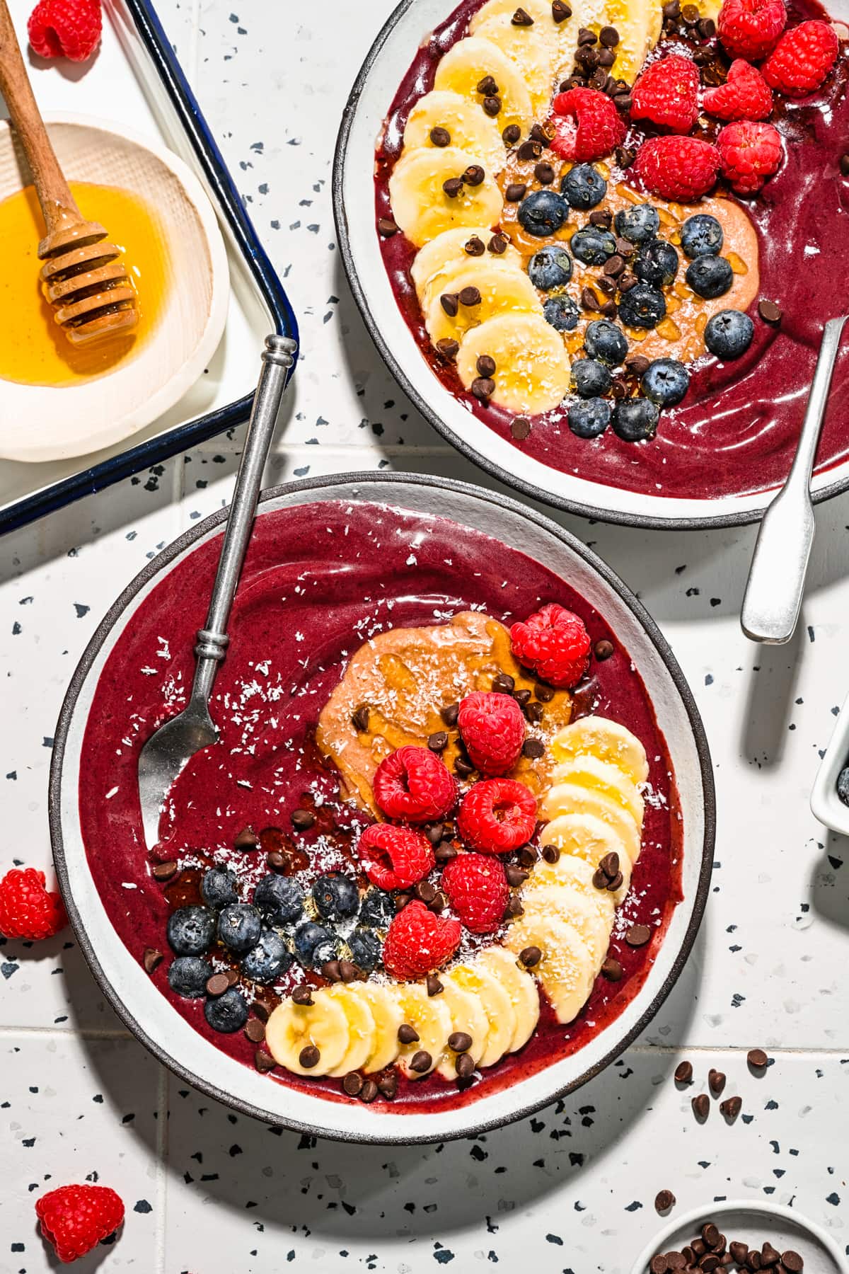 Overhead of the finished chocolate acai bowls with spoons in them.