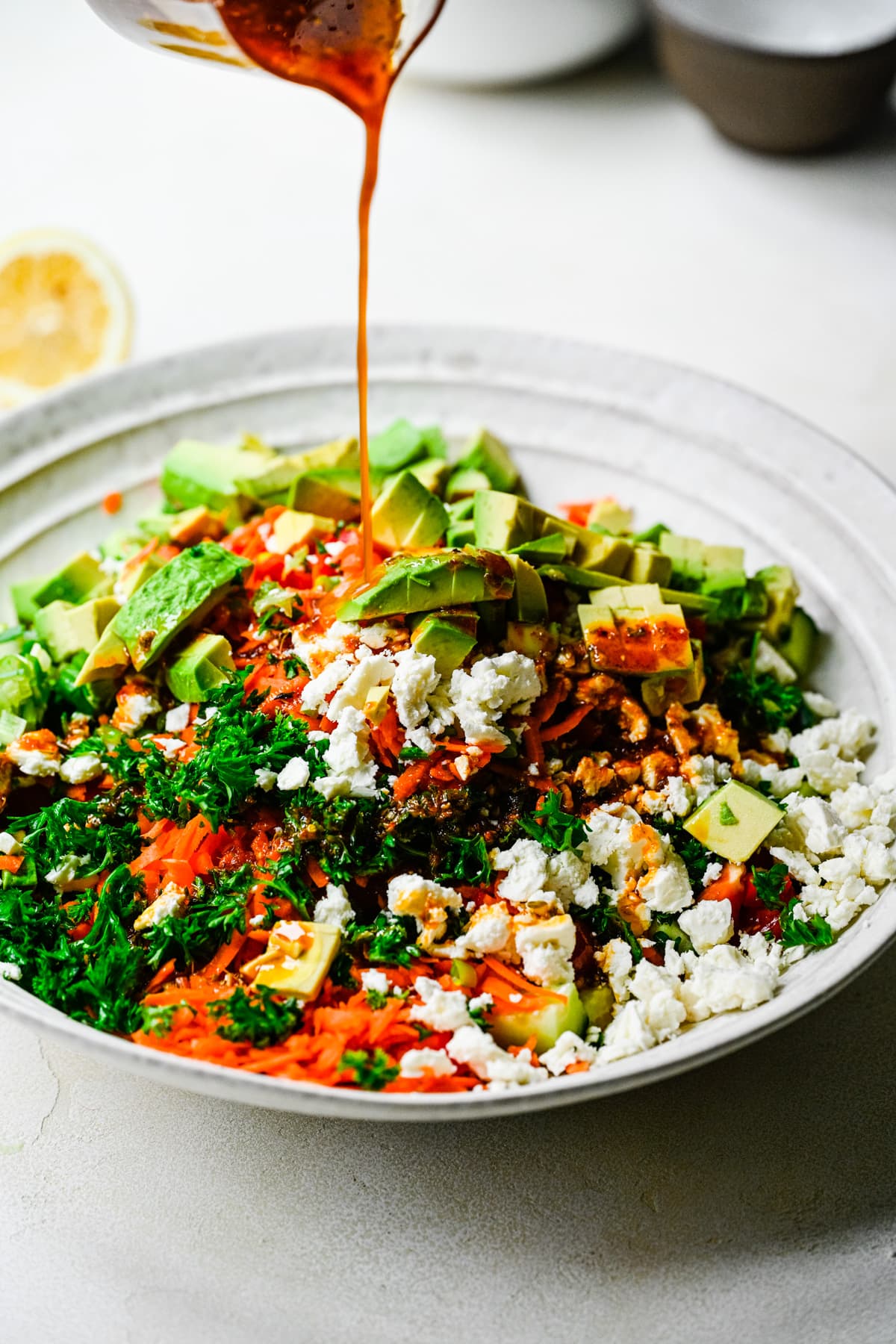 Pouring the harissa vinaigrette over a salad.