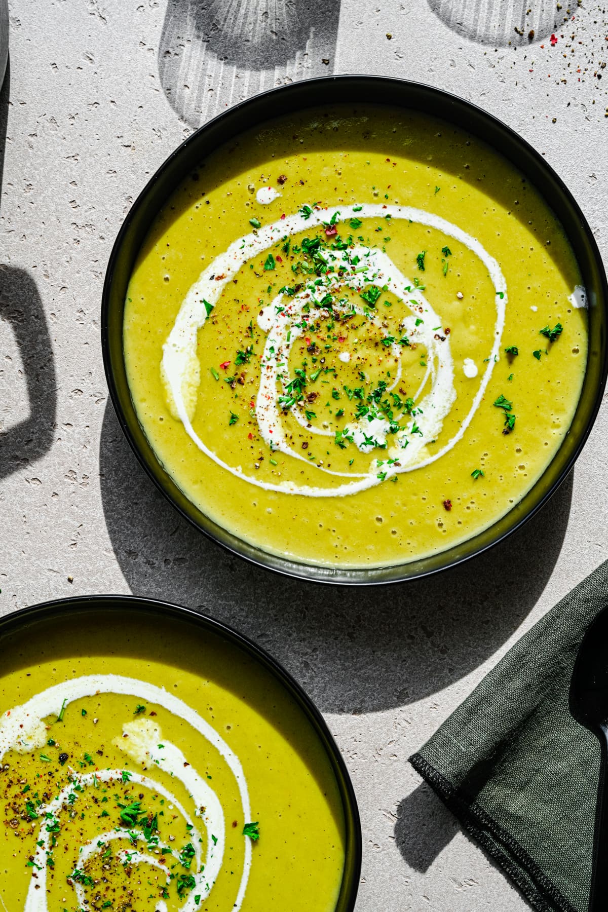 Overhead view of two bowls of soup with a cream swirl and pepper garnish.