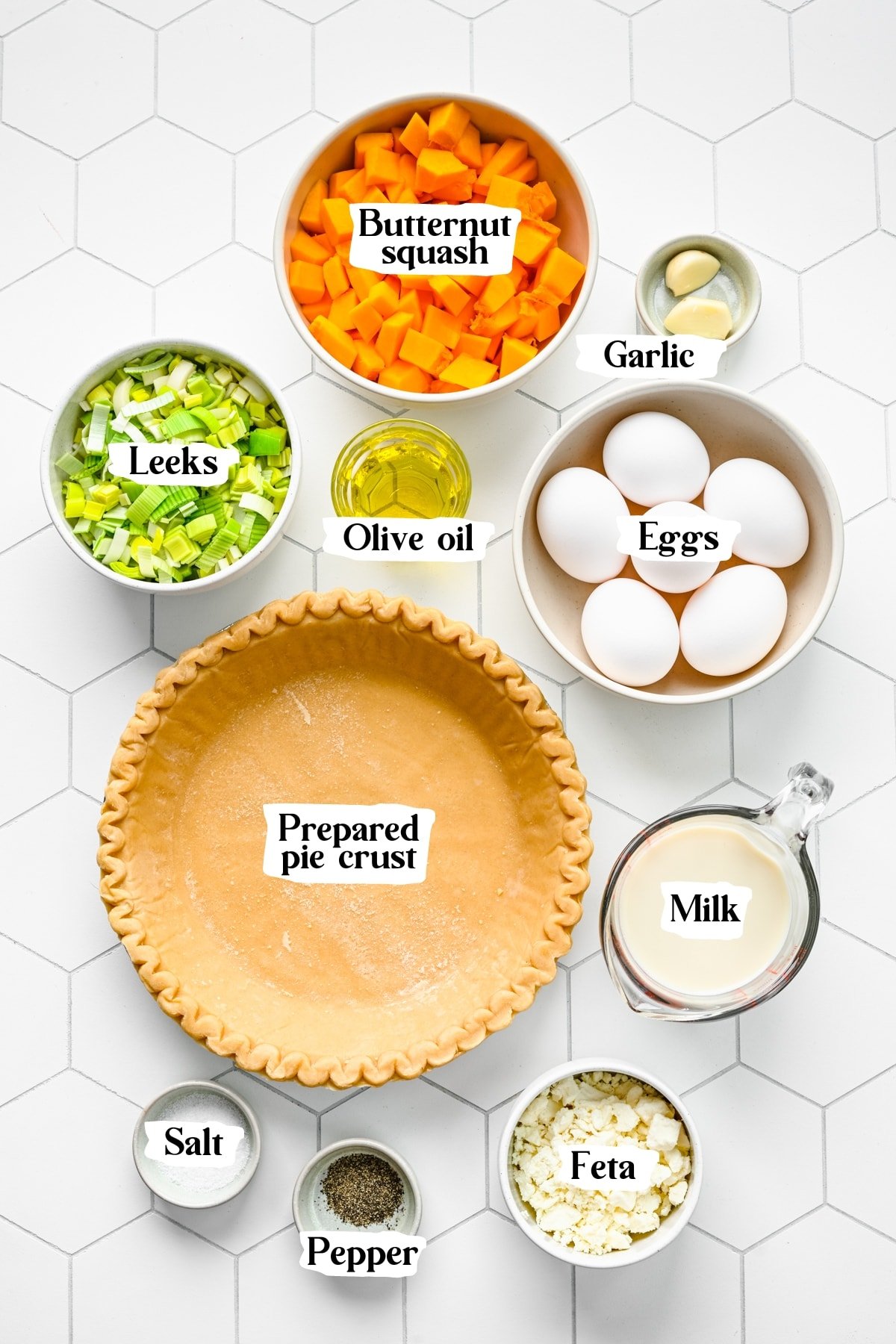 Overhead view of leek and squash quiche ingredients, including pie crust, eggs, and garlic.