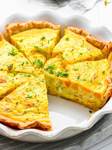 Overhead view of finished leek and squash quiche cut into slices.