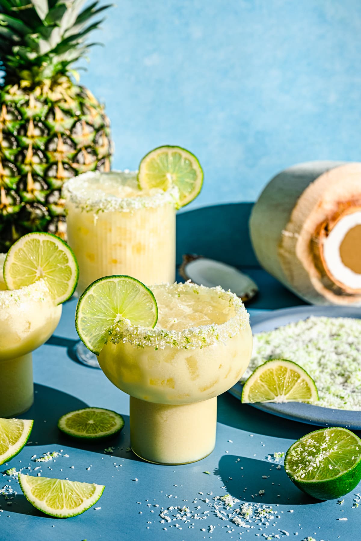 Finished pineapple coconut margaritas in glasses with lime slices and rim.