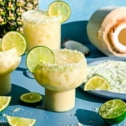 Finished pineapple coconut margaritas in glasses garnished with lime slices.