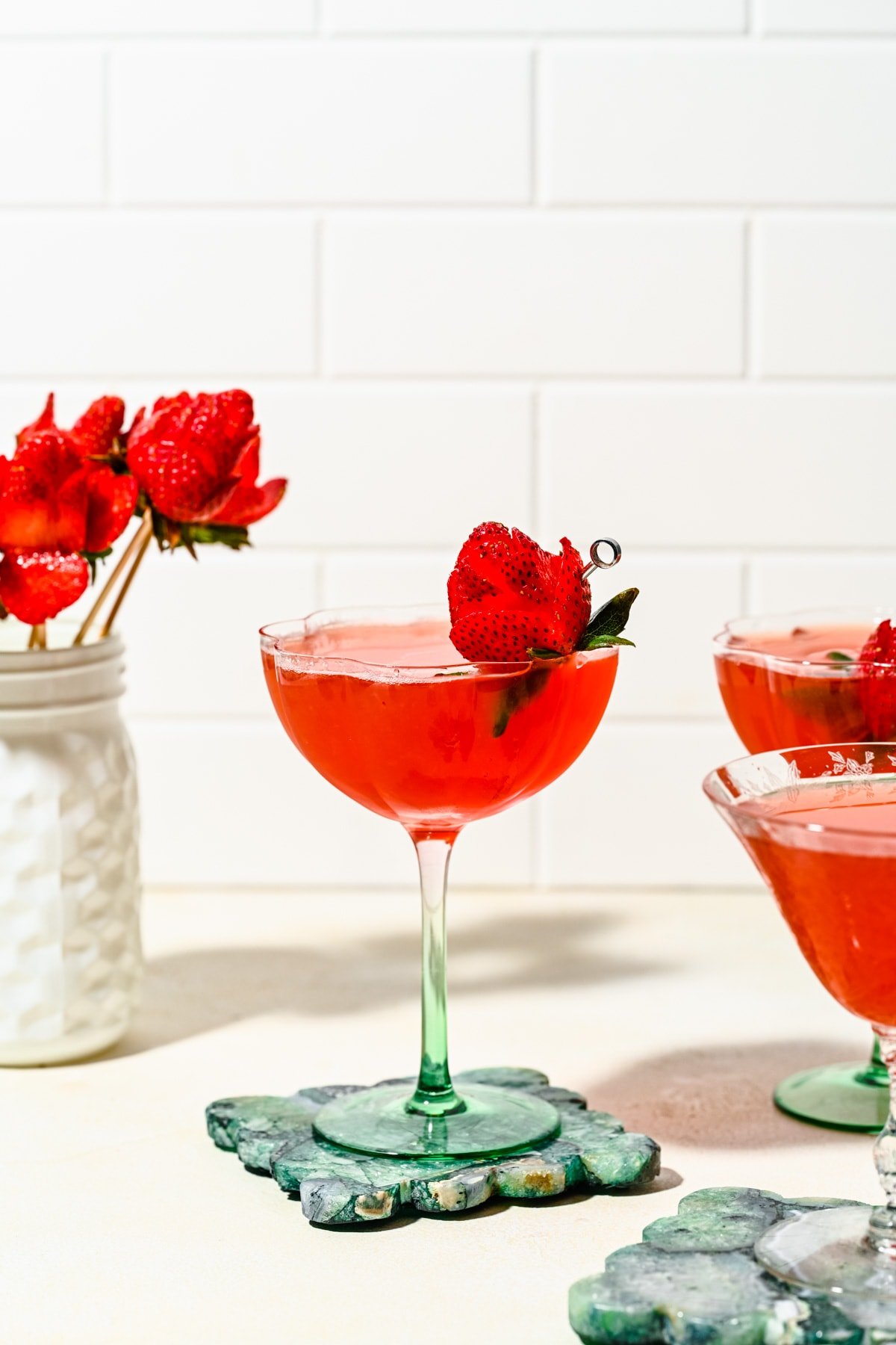 Finished strawberry martinis in martini glasses garnished with a strawberry rose.