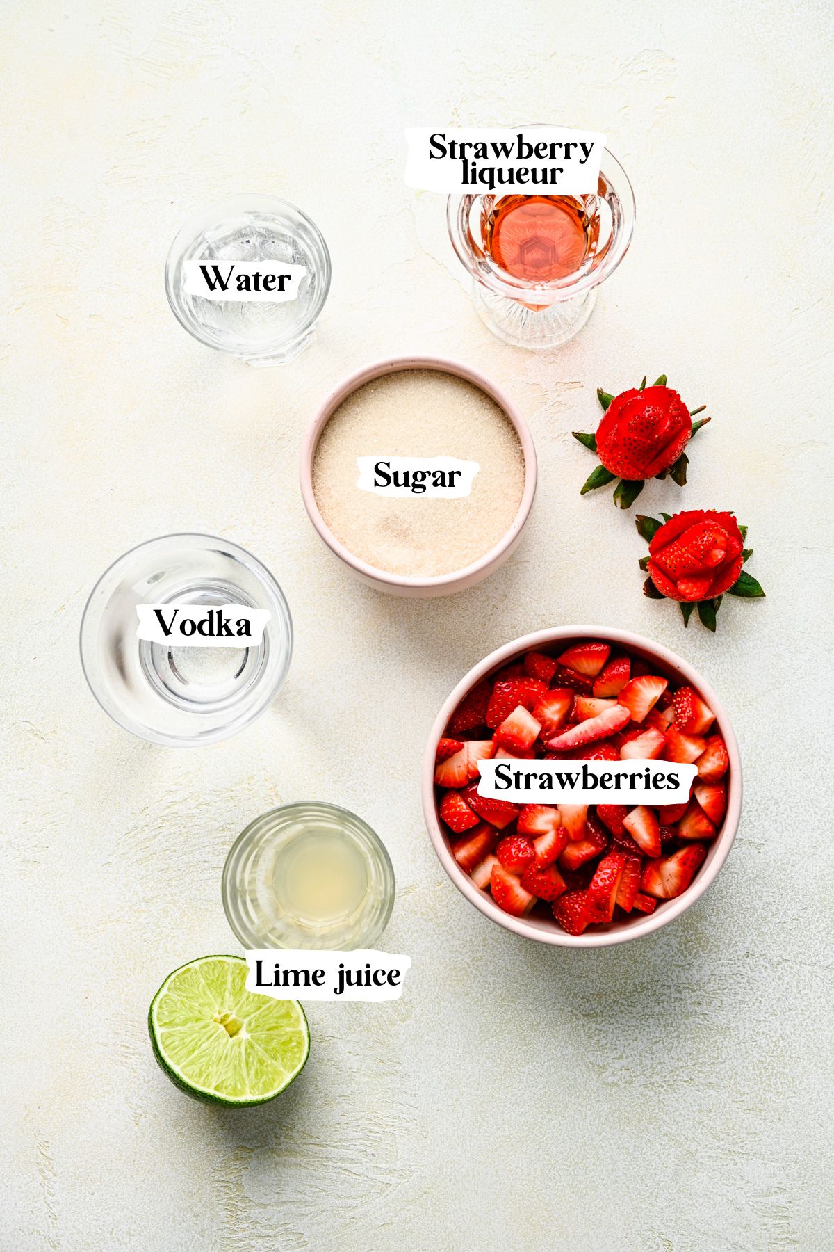 Overhead view of strawberry martini ingredients including vodka and lime juice.