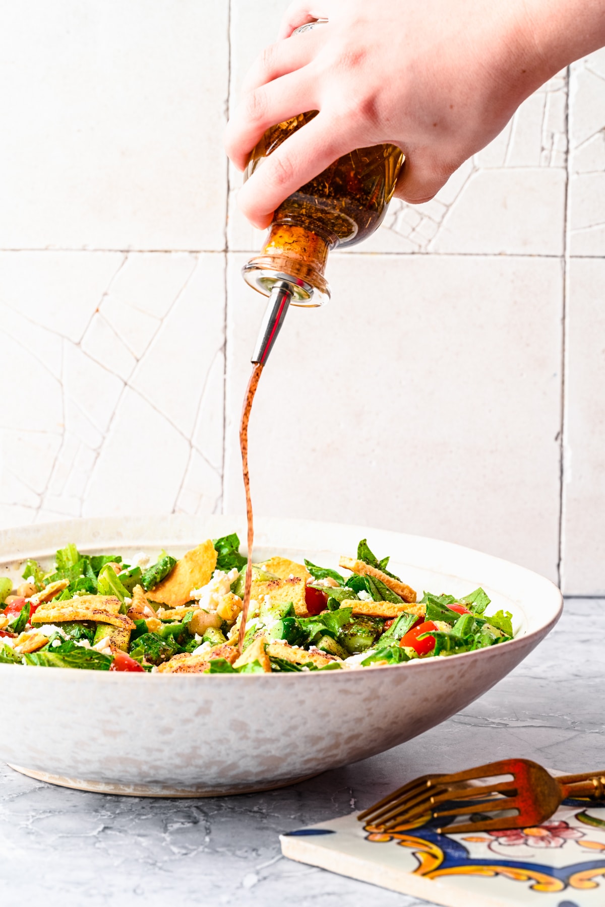 Drizzling the sumac dressing onto a salad.