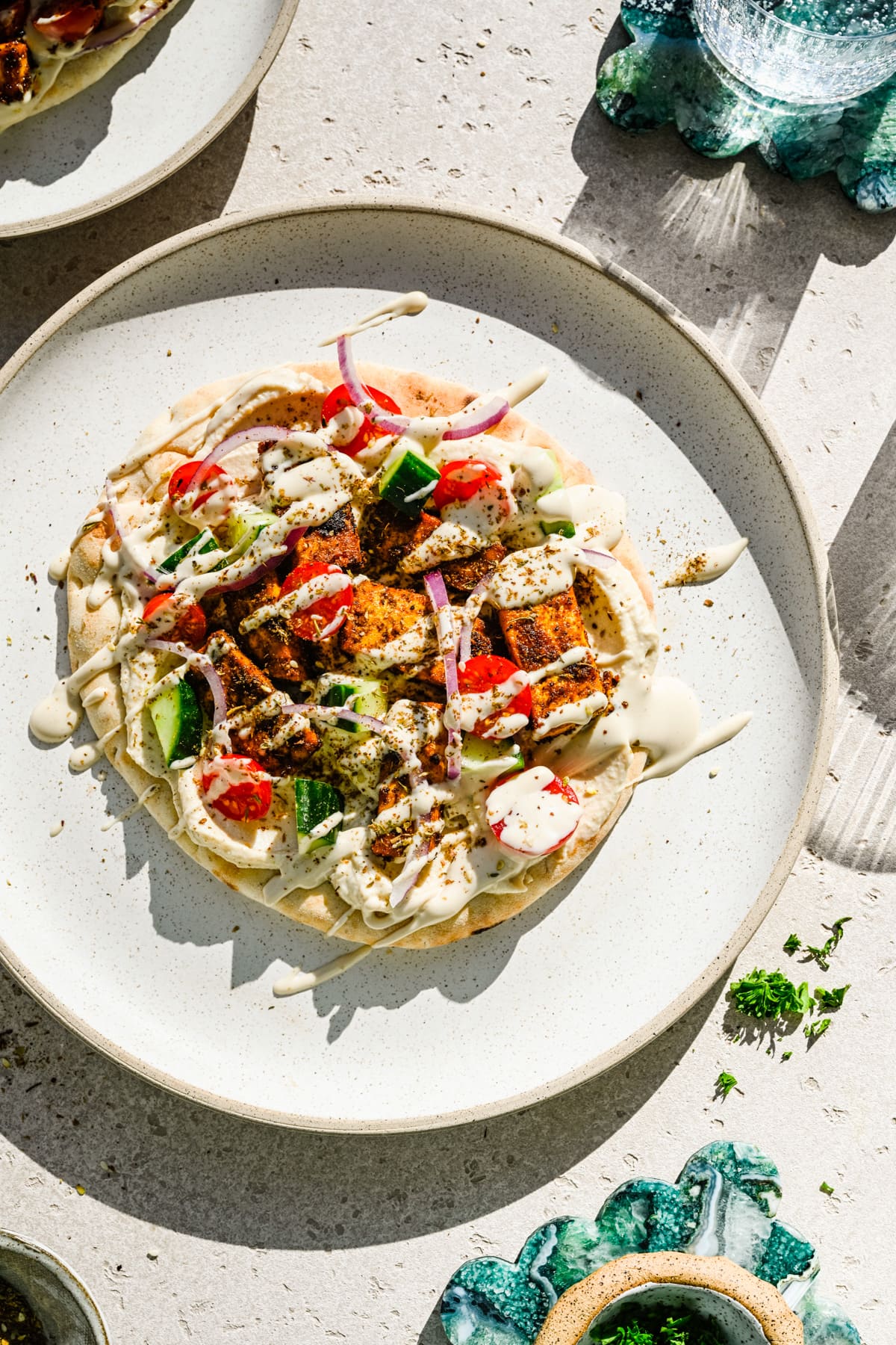 Finished tofu shawarma on a pita with veggies and sauce drizzle.