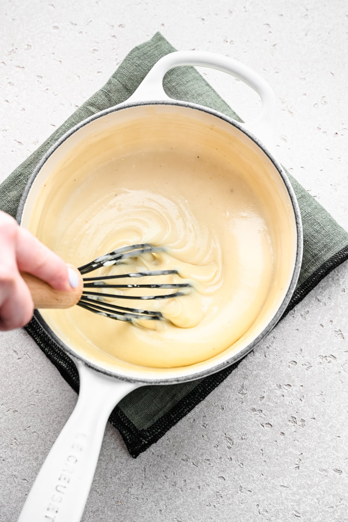 Overhead of whisking the vegan bechamel sauce in a saucepan.