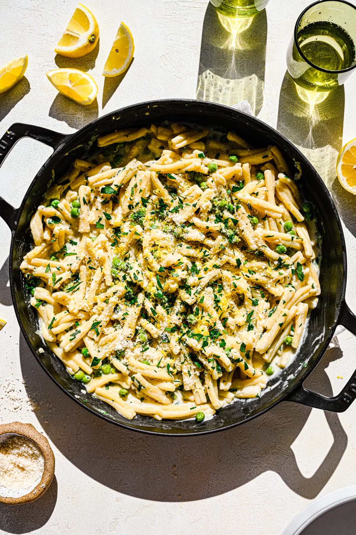 Overhead of the finished vegan lemon pasta in a skillet topped with lemon zest and herbs.