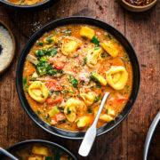 Overhead of the finished vegan tortellini soup in a black bowl.