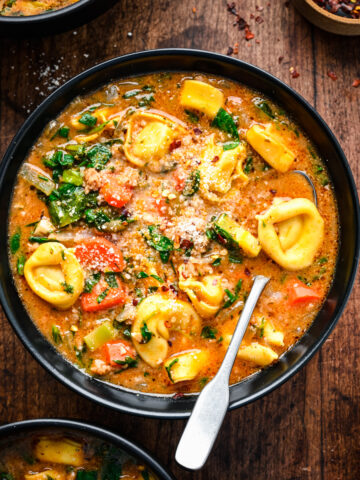 Overhead of the finished vegan tortellini soup in a black bowl.