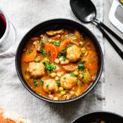 Overhead of the finished vegan stew with dumplings in a black bowl.