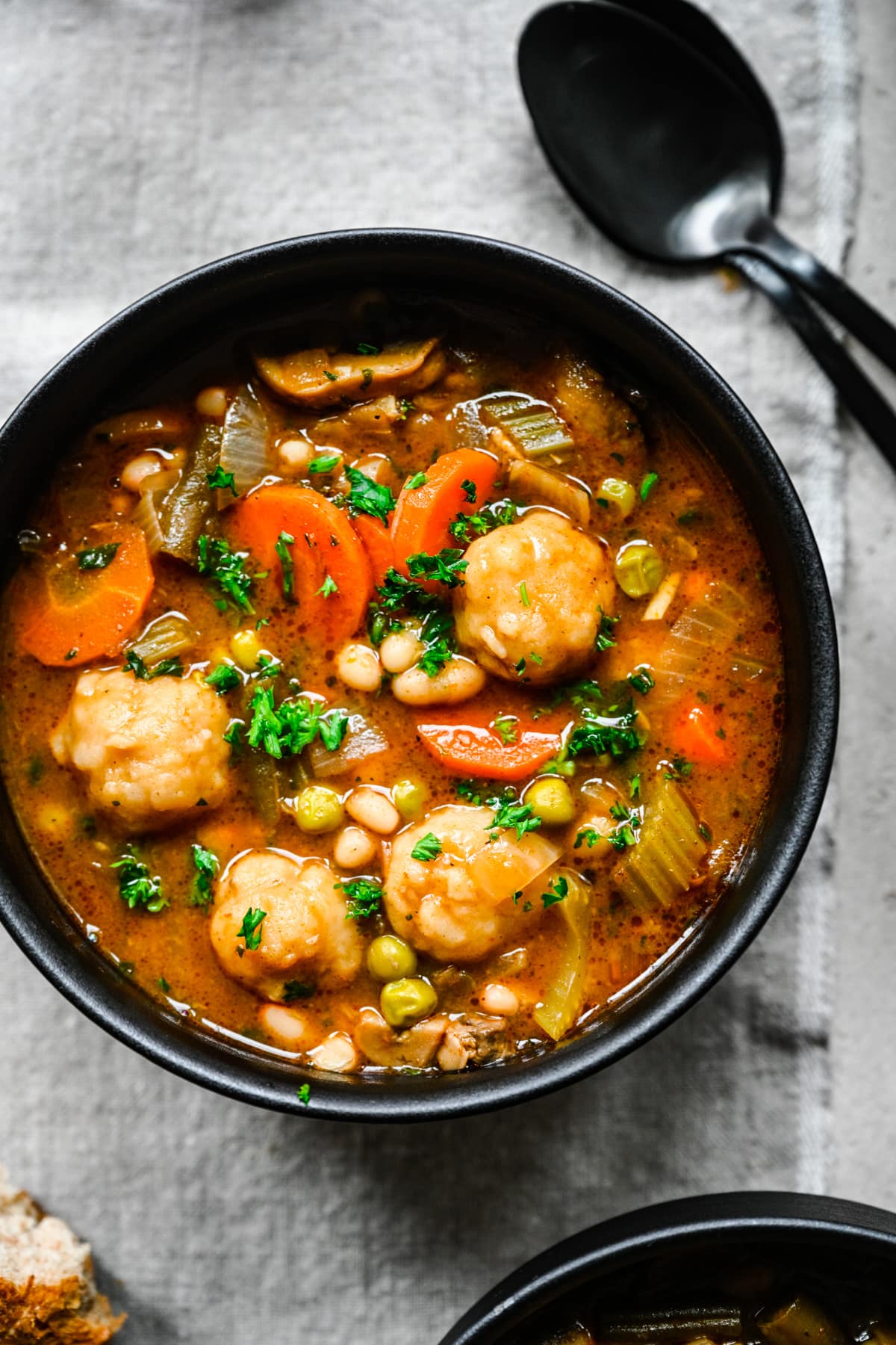 Close up overhead of the finished vegan stew and dumplings served in a black bowl.