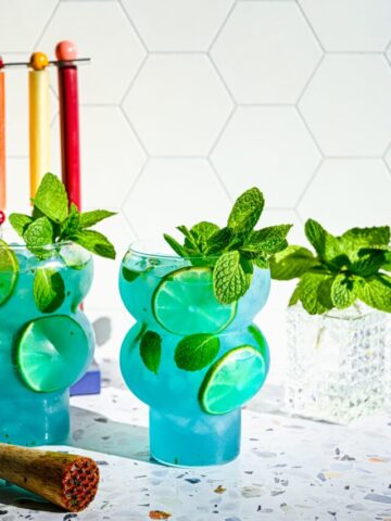 Front view of the finished blue mojitos in bubble glasses.