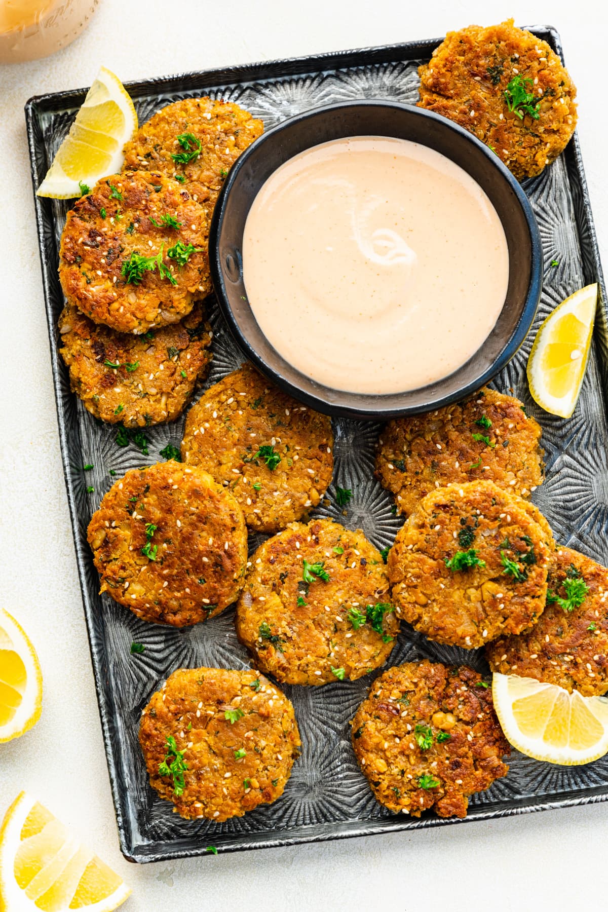 Overhead view of chickpea patties on a sheet pan with a dip.