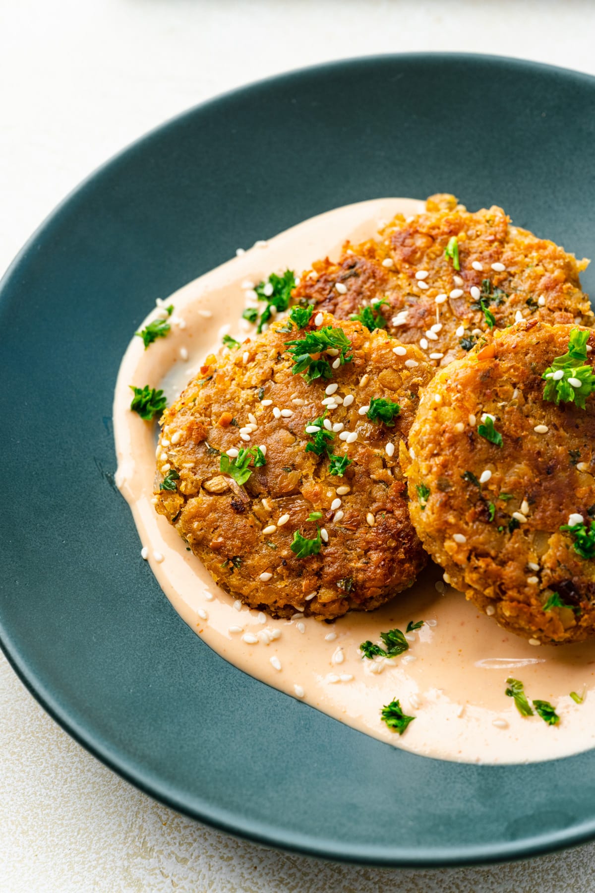 Overhead view of three chickpea fritters on a green plate.