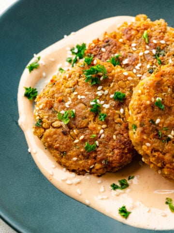 Overhead view of chickpea fritters on a green plate garnished with parsley.