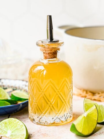 Finished lime simple syrup in a glass bottle.