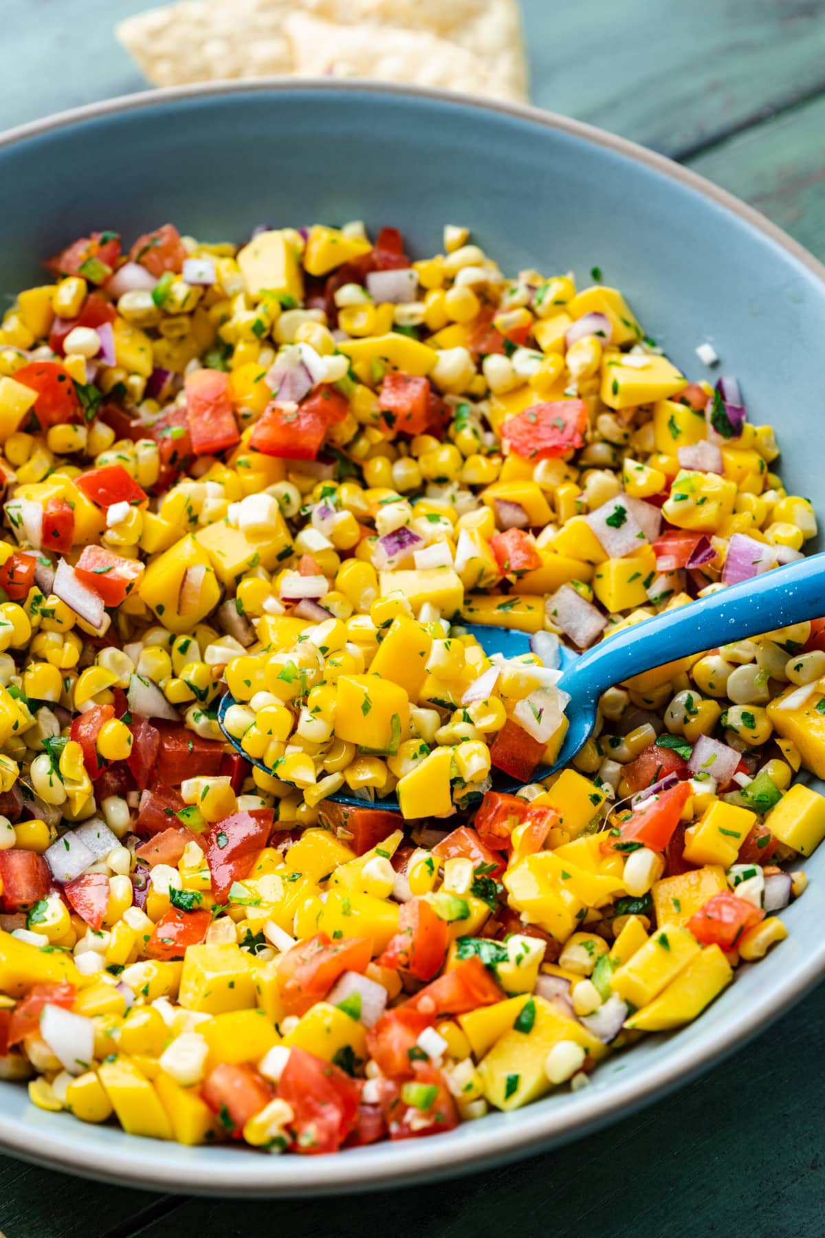 Spoon scooping the mango corn salsa out of the bowl.