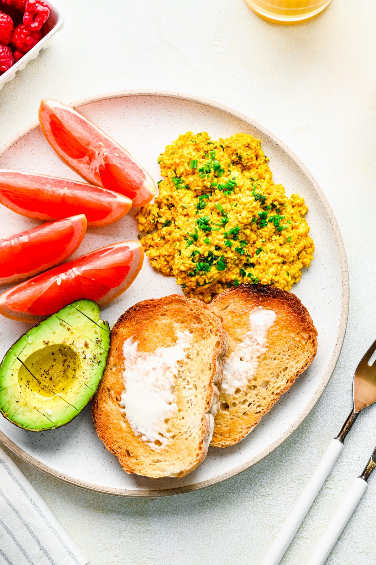 Overhead of the finished silken tofu scramble on a brunch plate with toast, avocado, and grapefruit.