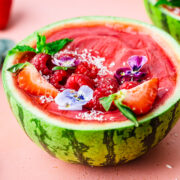 Side view of the finished watermelon smoothie bowls in a watermelon bowl.