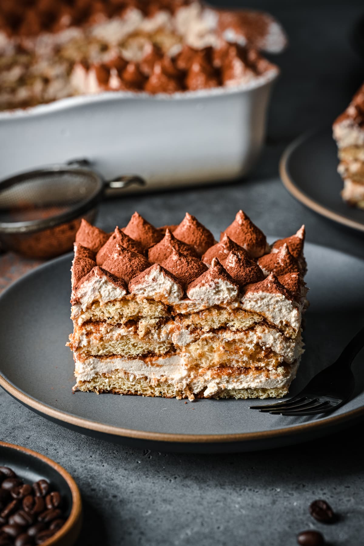 Close up side view of a slice of vegan tiramisu on a plate.