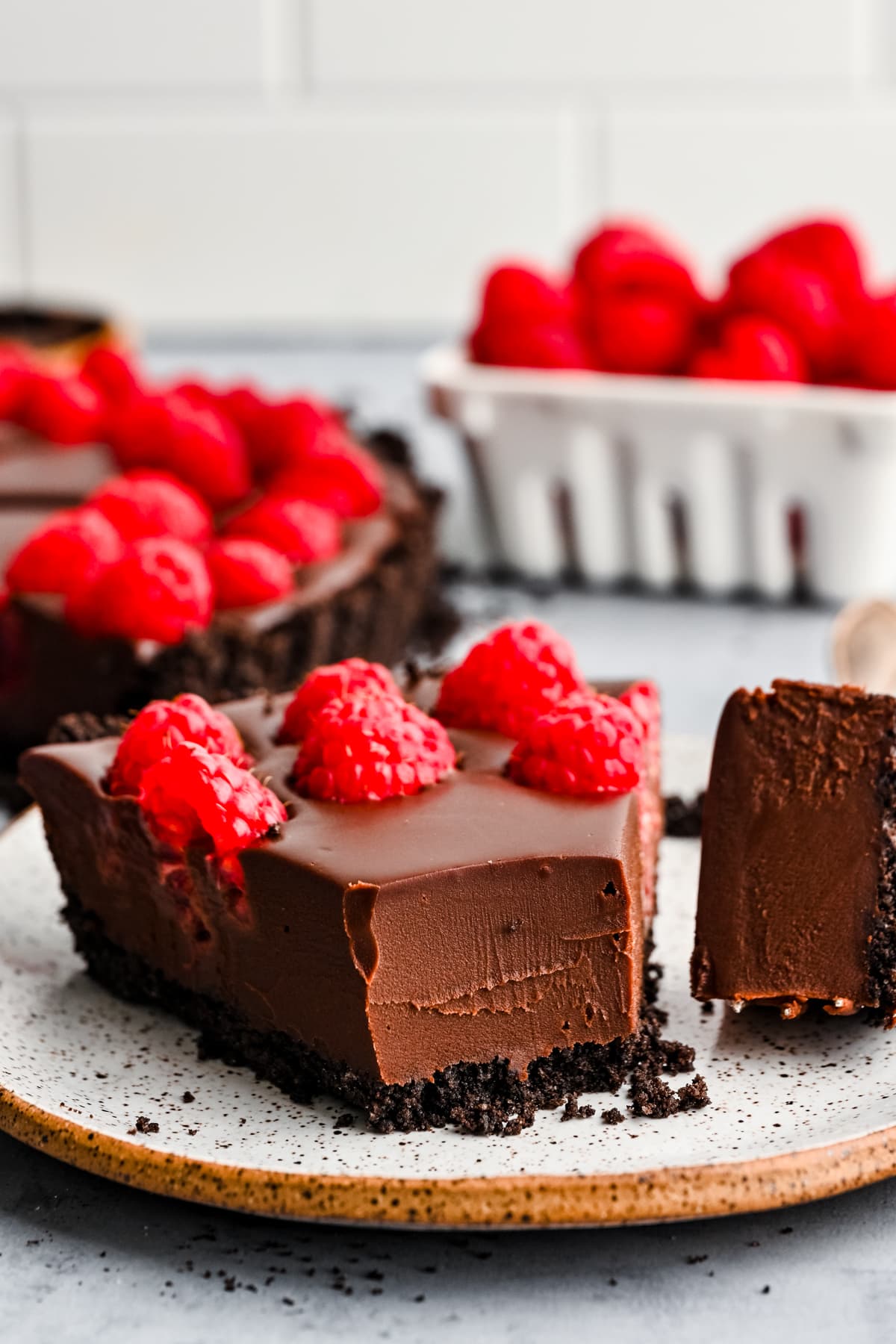 Close up view of slice of chocolate raspberry tart on a plate. 