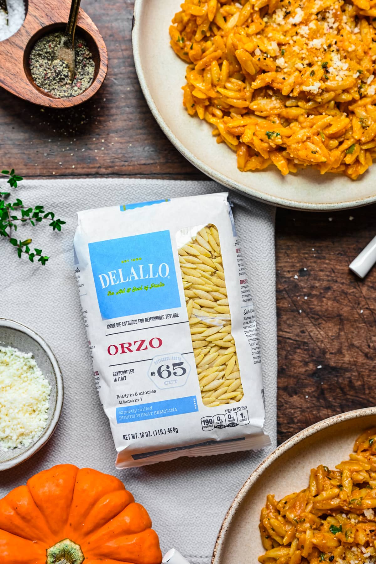 Overhead view of bag of DeLallo Orzo Pasta on table next to pumpkin orzo bowls.