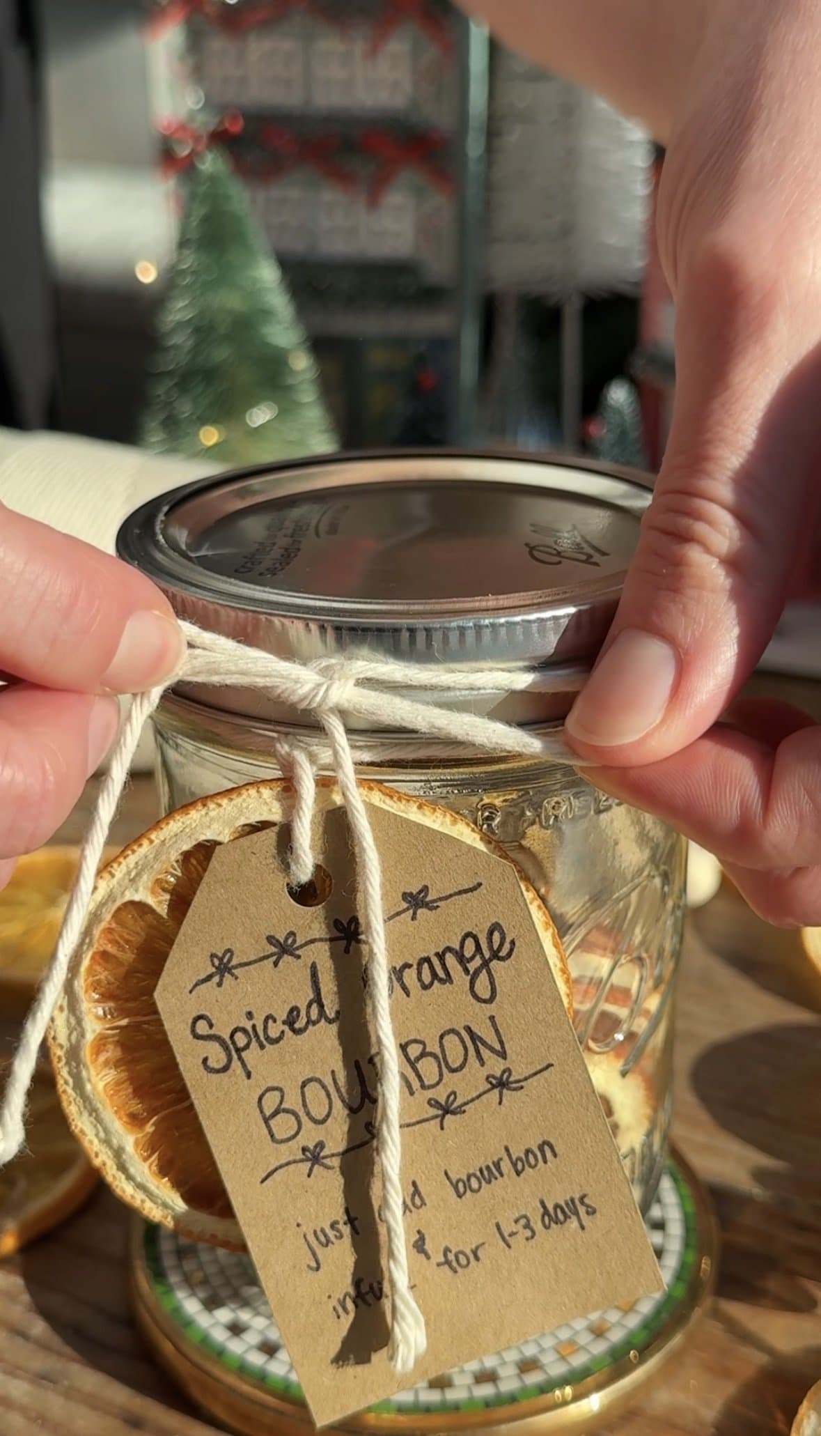 Person tying bow with twine to affix label to cocktail infusion kit.