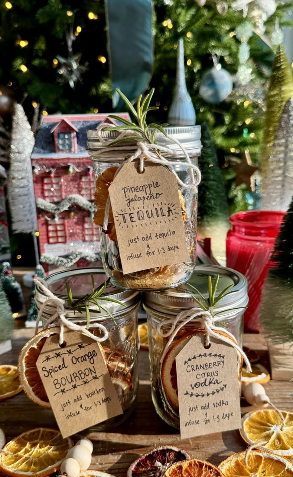 side view of 3 cocktail in a jar kits with christmas tree in background.