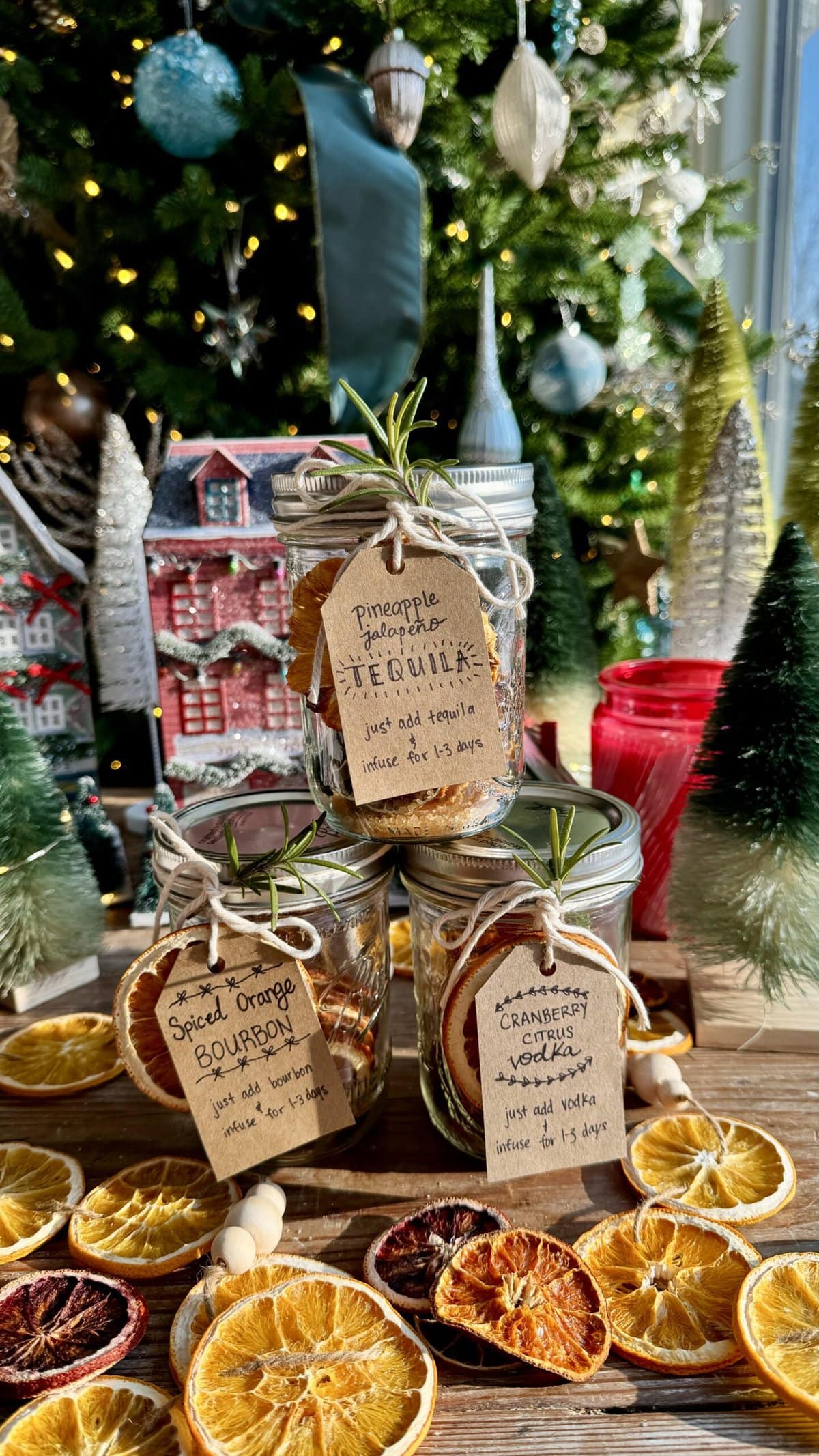 side view of 3 cocktail in a jar kits with christmas tree in background.