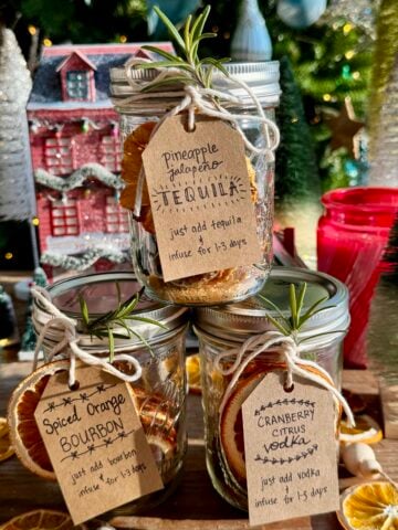 side view of 3 cocktail in a jar kits with christmas tree in background.