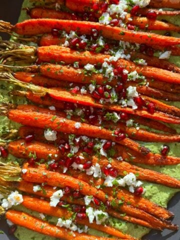 Overhead view of carrots atop green goddess dip.