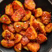 Crispy roasted baby potatoes with herbs and salt in a black bowl, perfect side dish.
