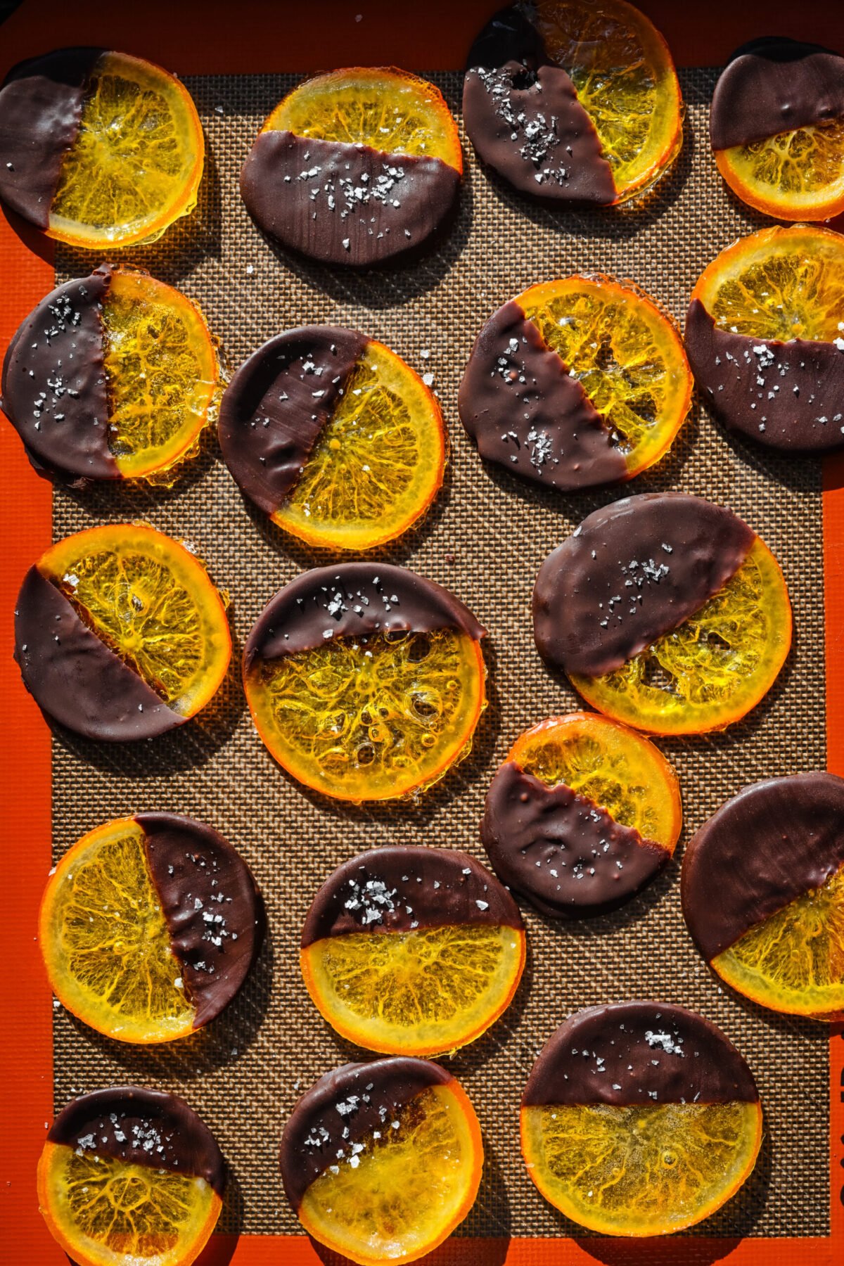 Overhead view of chocolate dipped oranges on a silicone mat.