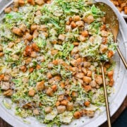 Crispy chicken Caesar salad with croutons and Parmesan cheese on a large platter.