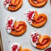 Overhead view of raspberry palmiers on a sheet pan.