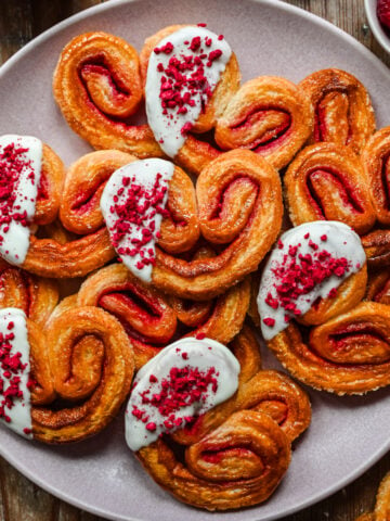 Overhead view of white chocolate dipped raspberry palmiers on a plate.